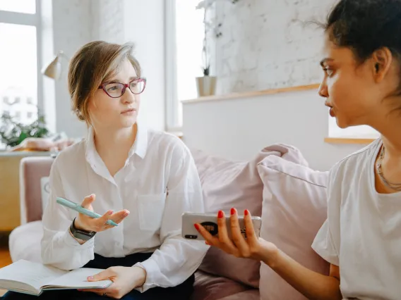 Two people sitting on a couch talking in a therapist office