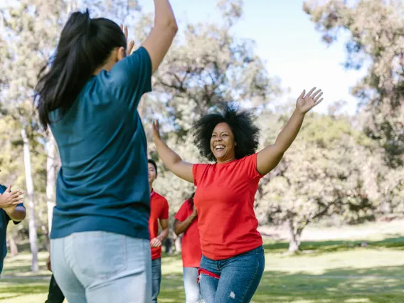 Two people with hands up smiling and interacting with group around them