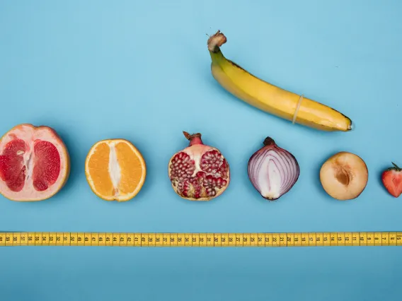 Banana with cross section of grapefruit, organge, onion, strawberry lined up with a tape measure underneath