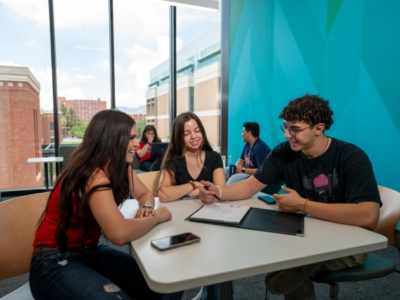 3 students sitting together at a table talking