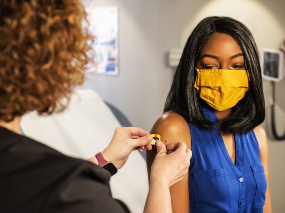 person in doctors office having band aide put on by clinician on arm