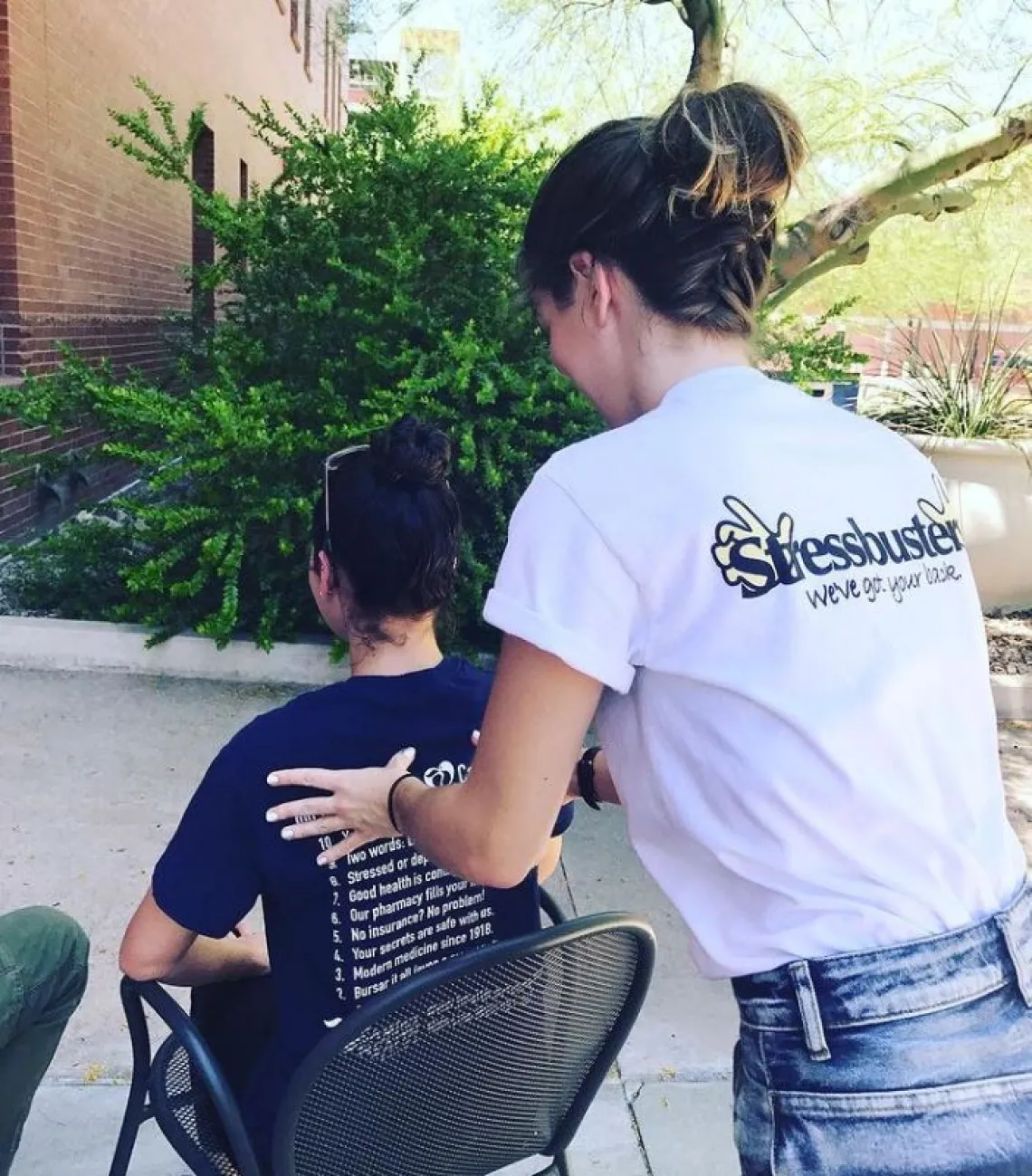 Person standing giving a seated person a back rub