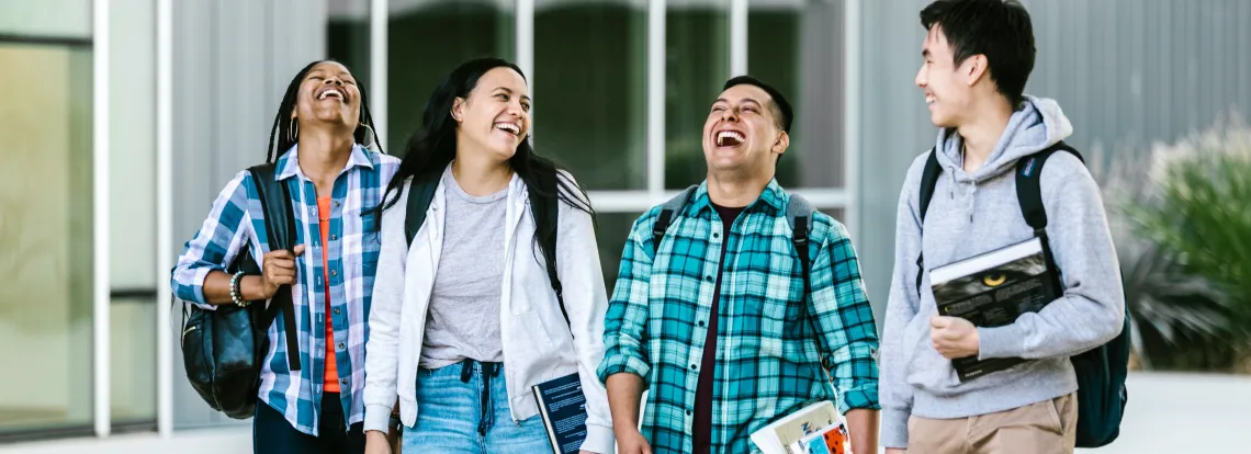 Group of 4 students laughing and walking