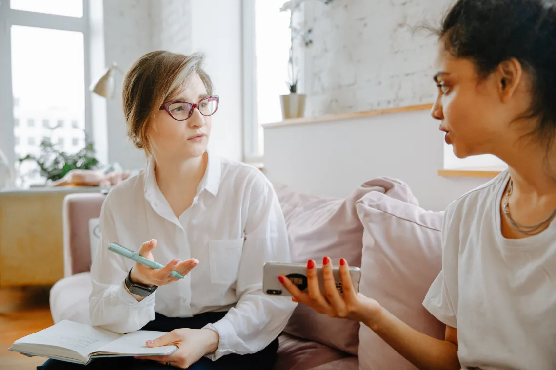 Two people sitting on a couch talking in a therapist office