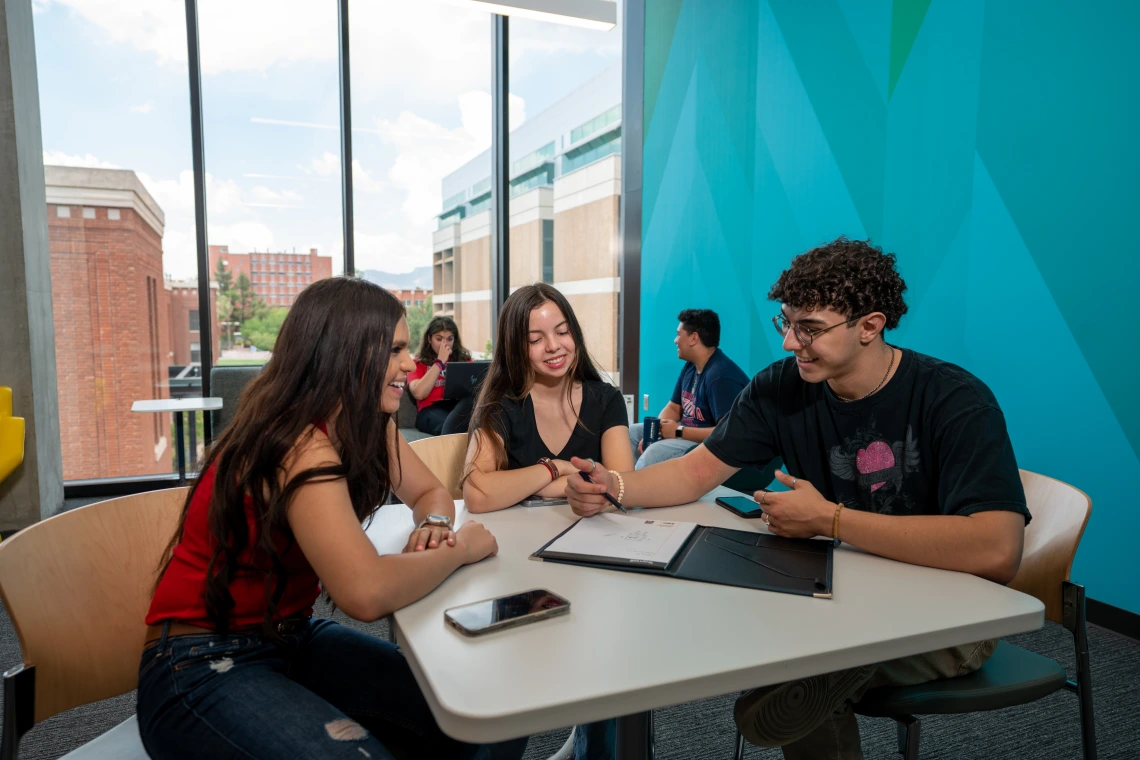 3 students sitting together at a table talking