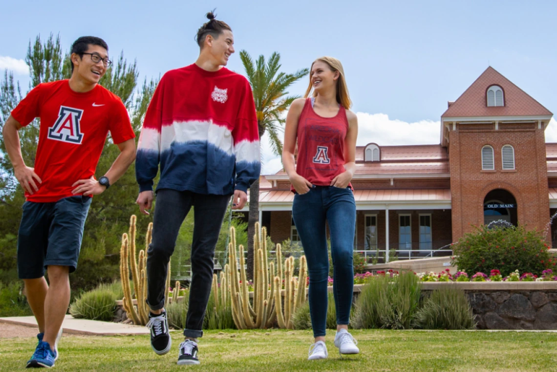 3 students walking and talking in front of old main