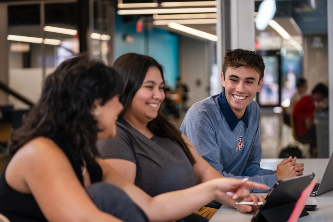 3 students sitting together smiling and talking