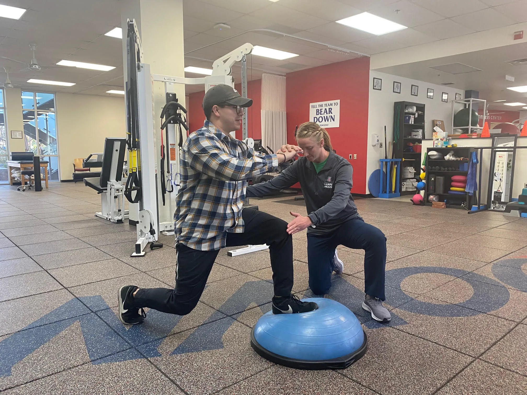 Person doing a lunge on a bousu ball with another person observing